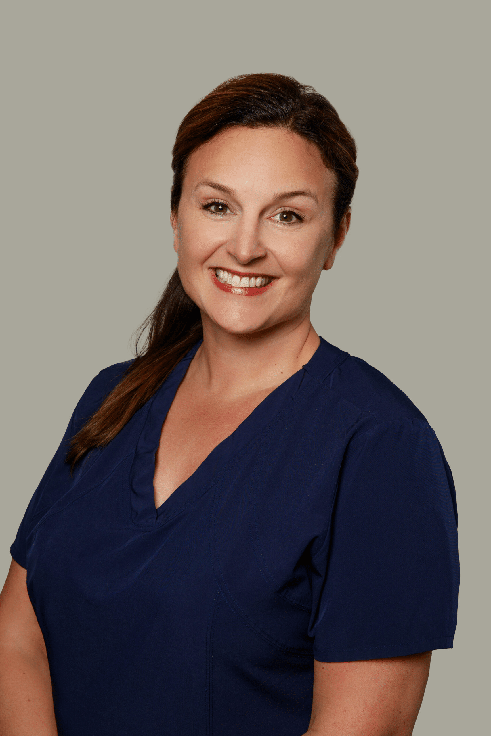 Staff member Carrie from Dr. Gary Wessels Inc. stands smiling in a professional office setting.