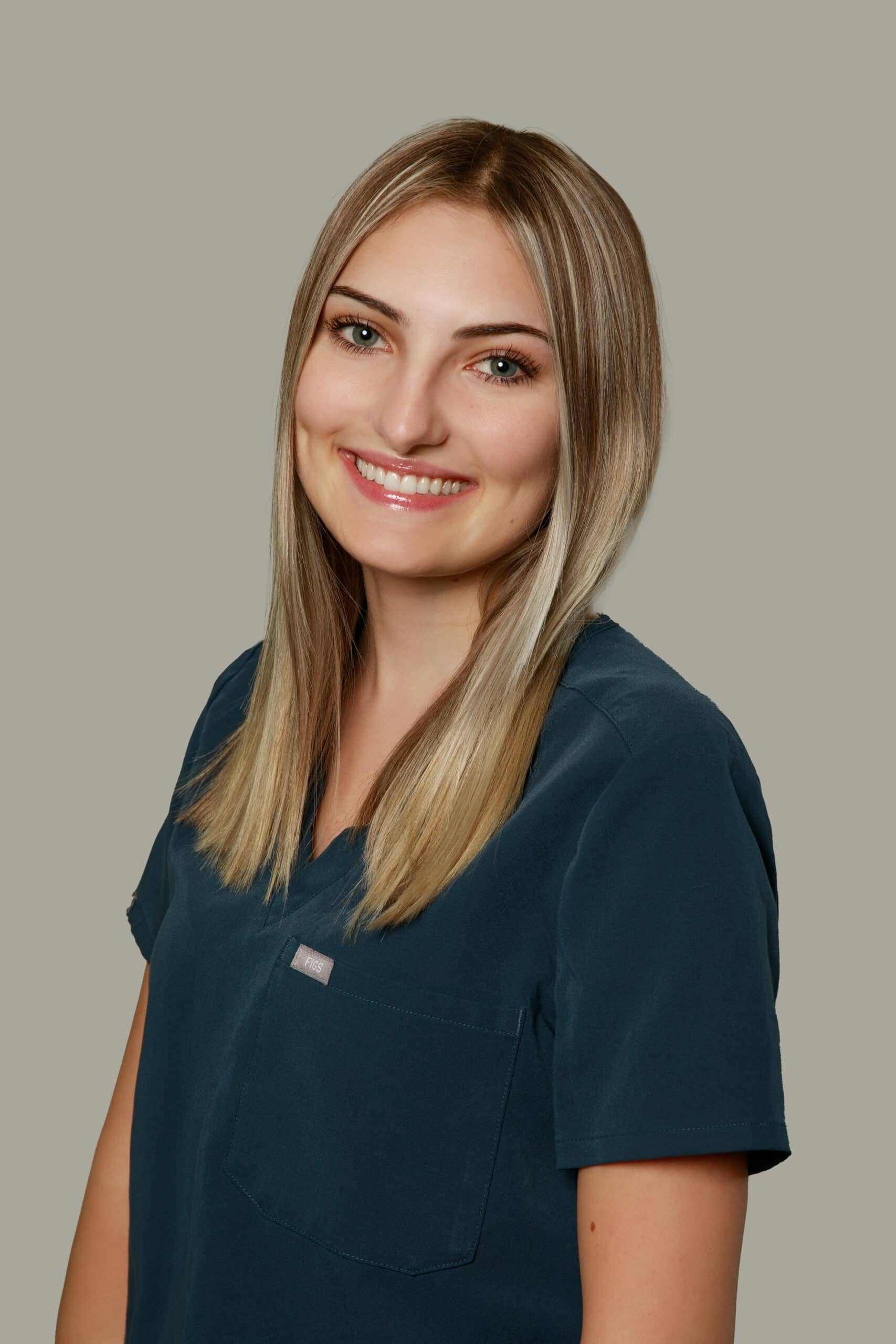 Staff member Zoe from Dr. Gary Wessels Inc. stands smiling in a professional office setting.